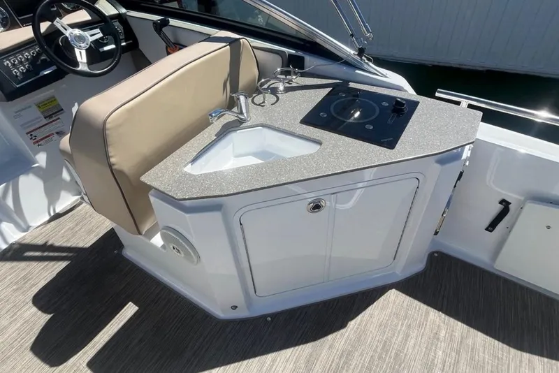 Slide: The Image of 2020 Four Winns V255 boat interior with kitchenette and steering wheel. - 12