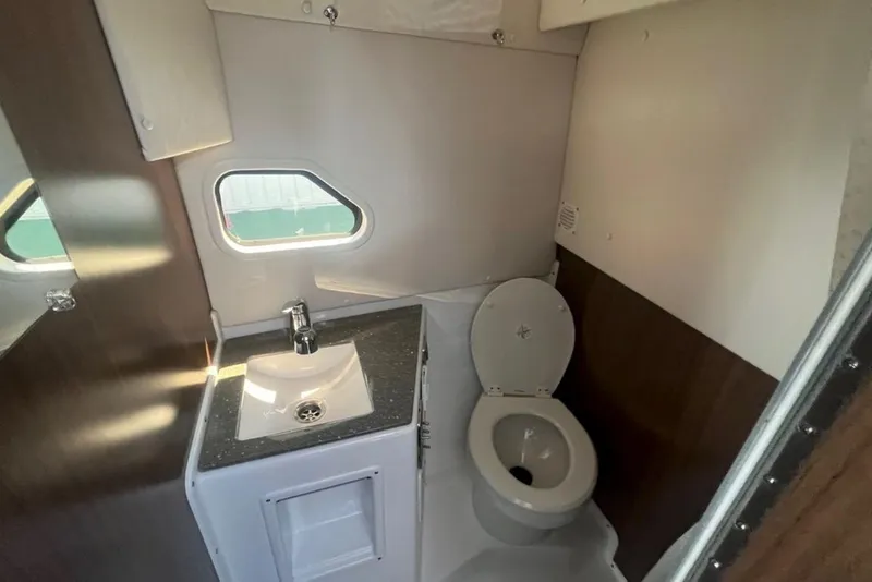 Slide: The Image of 2020 Four Winns V255 boat bathroom with sink, toilet, and window. - 22