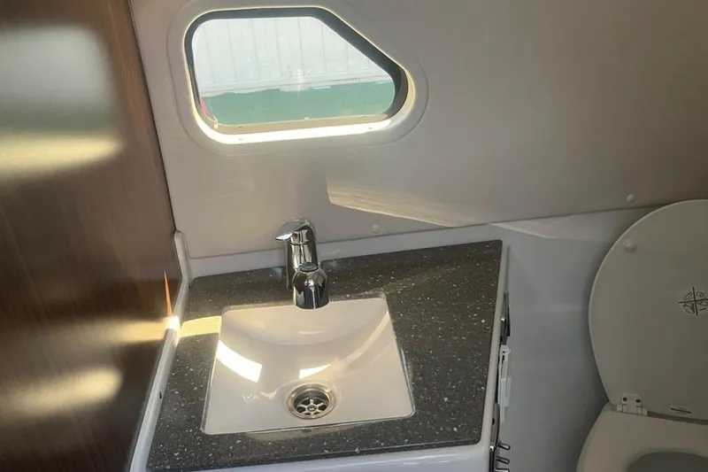 Slide: The Image of 2020 Four Winns V255 boat bathroom with sink, faucet, and window. - 23