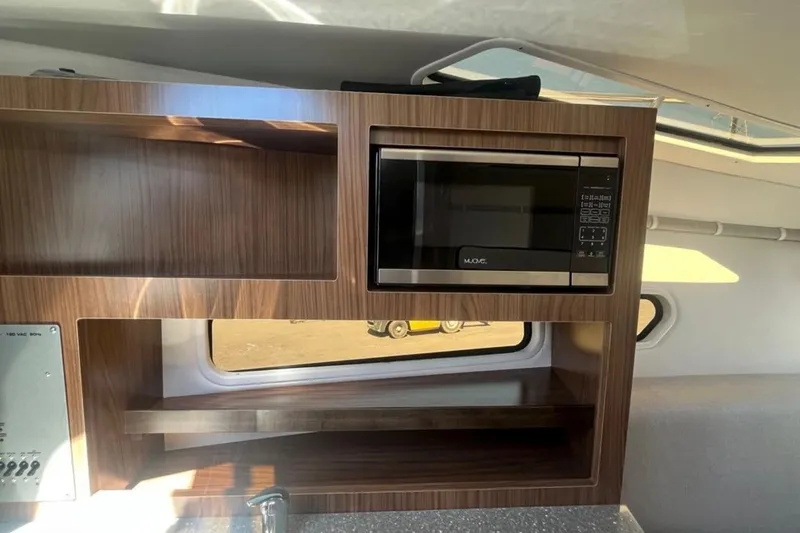 Slide: The Image of 2020 Four Winns V255 interior with microwave and wooden cabinetry. - 25