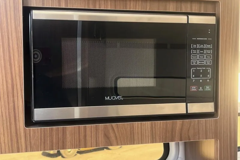 Slide: The Image of Built-in microwave in 2020 Four Winns V255 boat interior, featuring wood paneling. - 26