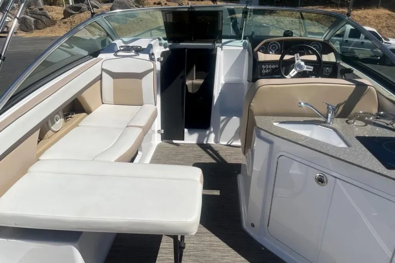 Slide: The Image of 2020 Four Winns V255 boat interior with seating, steering wheel, and kitchenette. - 7