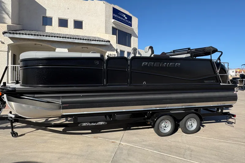 The Image of 2026 Premier 210 Sunsation RL pontoon boat on trailer, parked outside a building. - 0