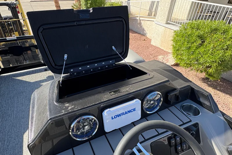 Slide: The Image of 2026 Premier 210 Sunsation RL dashboard with open storage, Lowrance display, and steering wheel. - 11