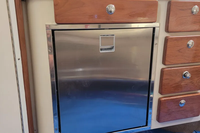 Slide: The Image of Stainless steel fridge and wooden drawers in 2007 Pursuit OS 335 Offshore boat interior. - 10