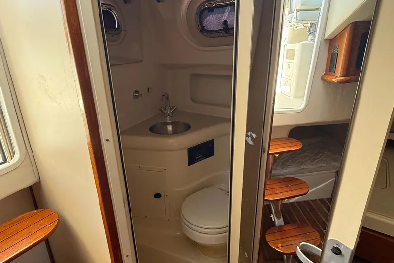 Slide: The Image of 2007 Pursuit OS 335 Offshore boat interior with compact bathroom and wooden steps. - 11
