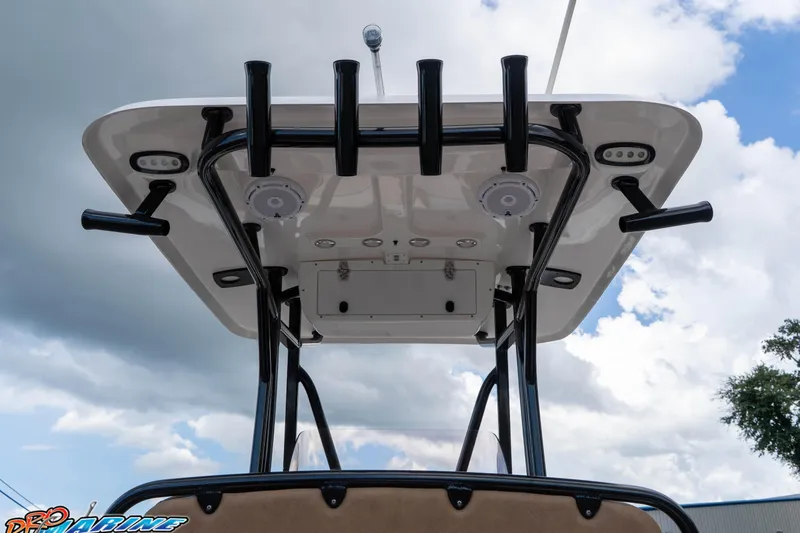 Slide: The Image of 2023 Sea Hunt Ultra 234 boat T-top with rod holders and speakers under cloudy sky. - 23