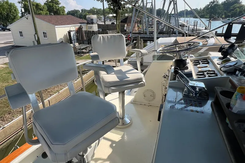 Slide: The Image of 1989 Egg Harbor 33 Convertible boat helm with white captain chairs and control panel. - 11
