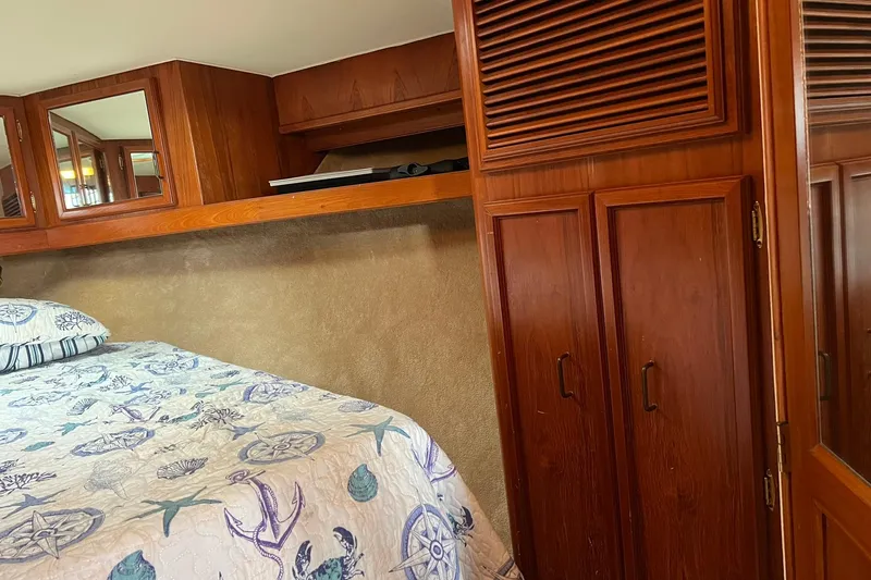 Slide: The Image of 1989 Egg Harbor 33 Convertible cabin with wooden cabinets and nautical-themed bedding. - 43