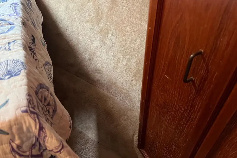 Slide: The Image of Interior of 1989 Egg Harbor 33 Convertible, featuring a quilted bedspread and wooden cabinet. - 46