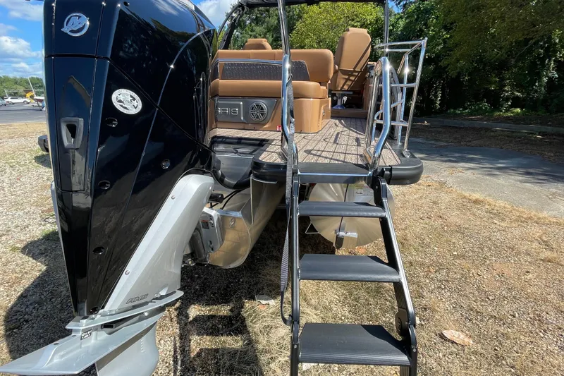 Slide: The Image of 2026 Harris Solstice 250 SLDH pontoon boat with rear ladder and seating, parked outdoors. - 2