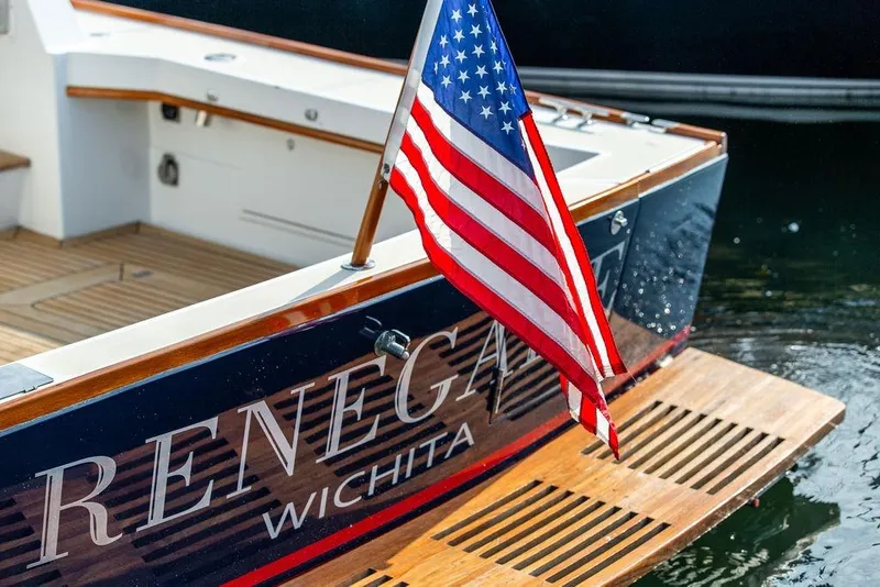 Slide: The Image of 1994 Little Harbor Express boat with American flag, named "Renegade," docked in water. - 76