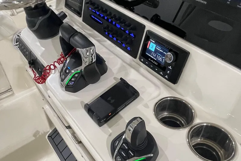 Slide: The Image of 2024 Cobia 265 Open Center Console dashboard with controls, radio, and cup holders. - 16