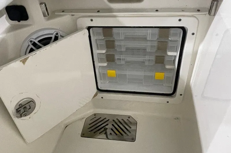 Slide: The Image of 2024 Cobia 265 Open Center Console storage compartment with tackle boxes and speaker. - 20