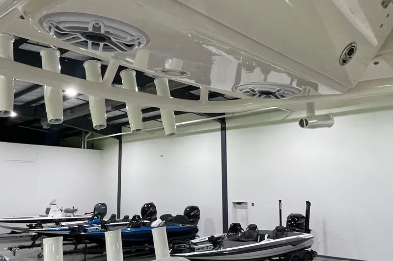 Slide: The Image of 2024 Cobia 265 Open Center Console boat with rod holders and speakers in a showroom. - 23