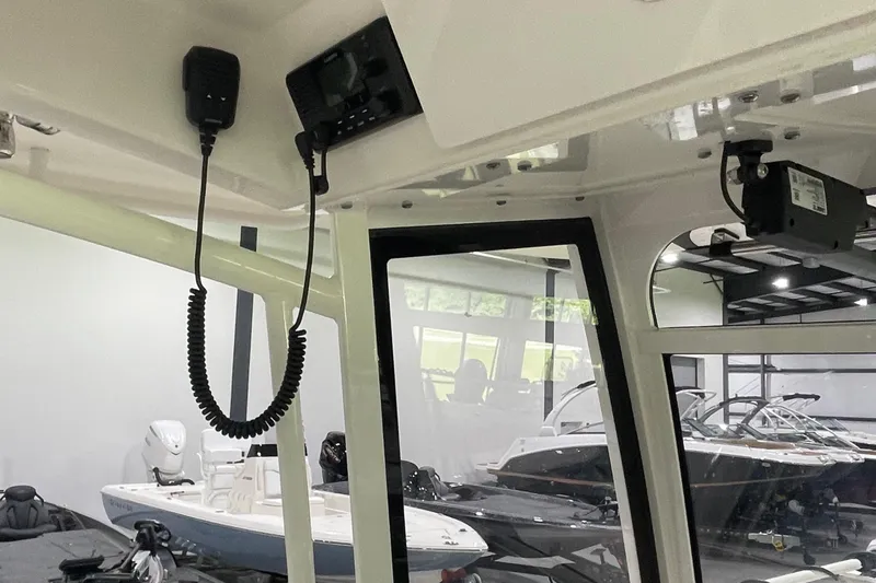 Slide: The Image of 2024 Cobia 265 Open Center Console interior with radio equipment and boat showroom view. - 24