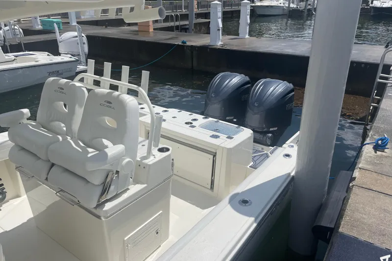 Slide: The Image of 2024 Cobia 265 Open Center Console boat docked, featuring dual outboard engines. - 5