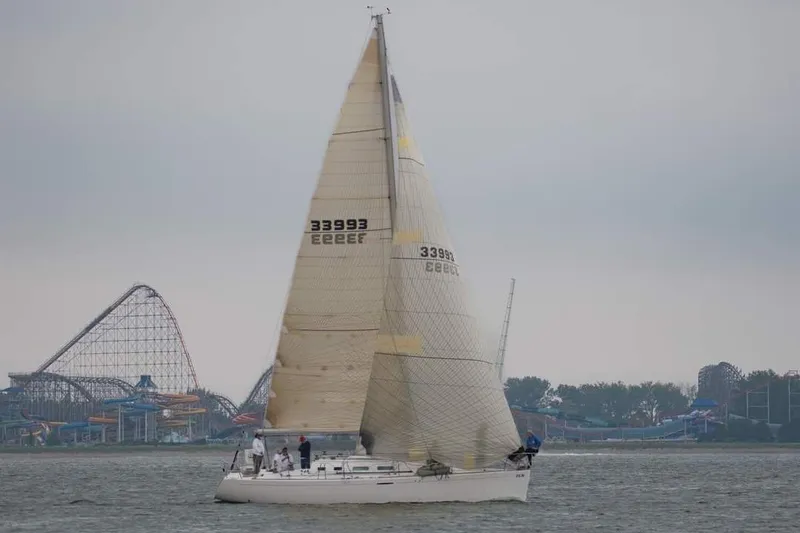 Slide: The Image of 2001 Beneteau First 40.7 sailboat on water near amusement park. - 2