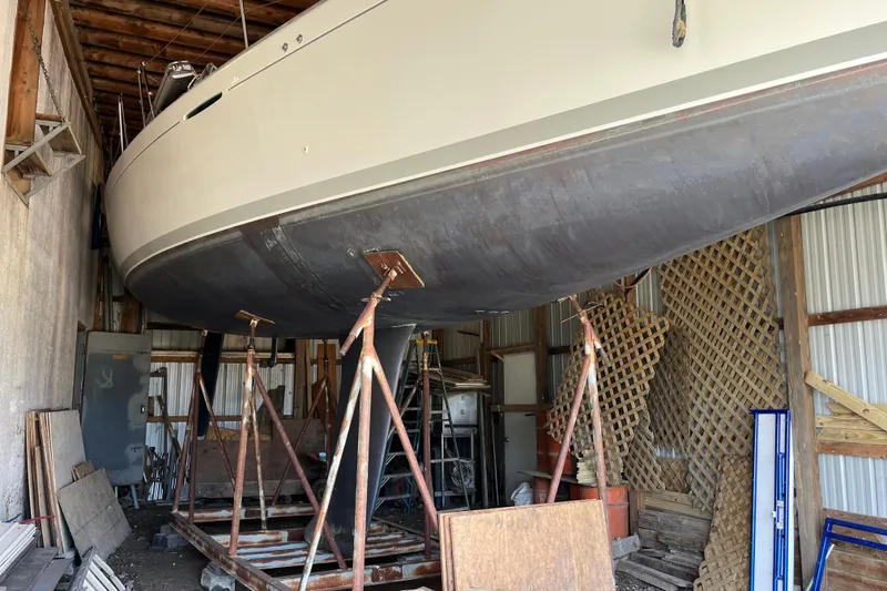 Slide: The Image of 2001 Beneteau First 40.7 sailboat in storage, supported by stands in a wooden shed. - 22