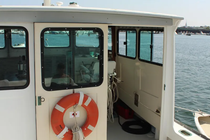 Slide: The Image of 1992 Novi 32 Downeast boat with life preserver, docked by the water. - 17