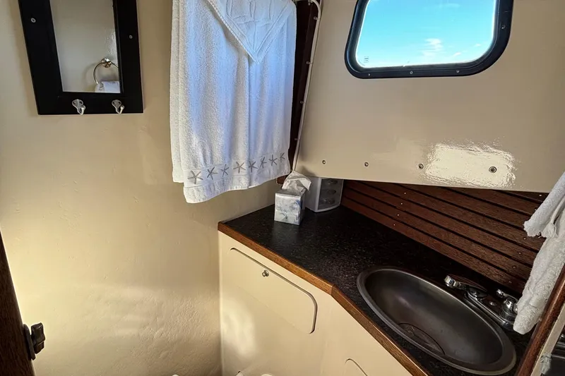 Slide: The Image of 1982 Stanley Greenwood/Novi 32 Downeast boat bathroom with sink, towel, and window. - 32