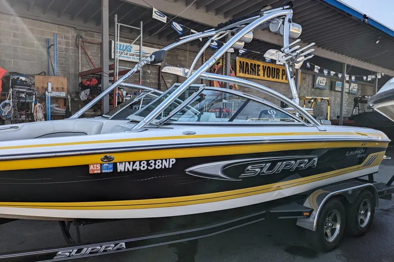Slide: The Image of 2005 Supra Launch 21 V boat with yellow and black design in a garage setting. - 1
