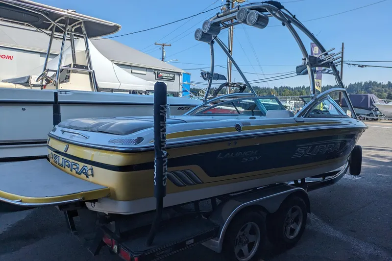 Slide: The Image of 2005 Supra Launch 21 V boat on trailer at marina, featuring wakeboard tower. - 5