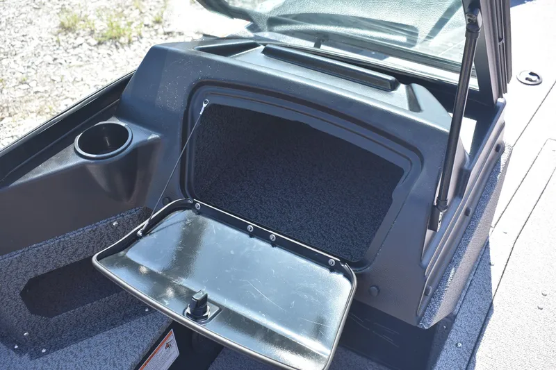 Slide: The Image of 2026 Lund 1800 Explorer Sport boat storage compartment with open lid and cup holder. - 9
