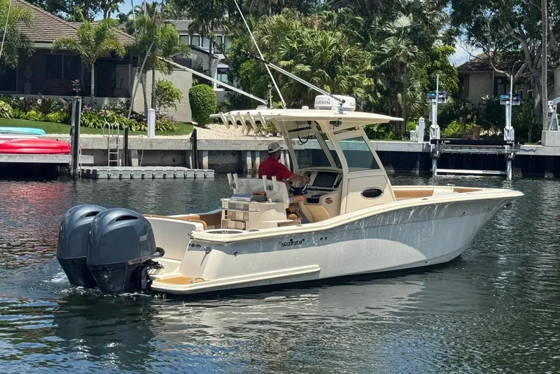 Slide: The Image of 2013 Scout 275 LXF boat cruising on a sunny waterfront. - 12