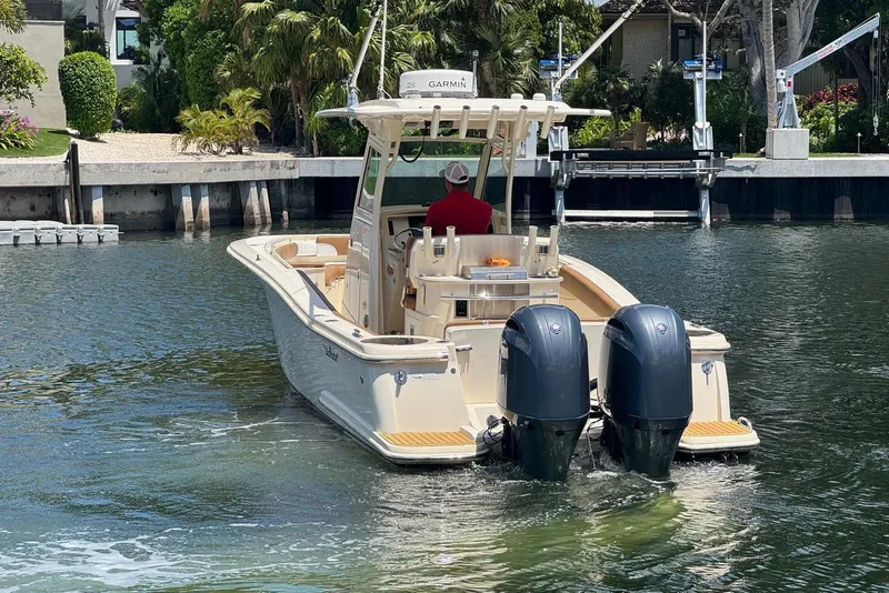 Slide: The Image of 2013 Scout 275 LXF boat with dual engines navigating a calm waterway. - 13