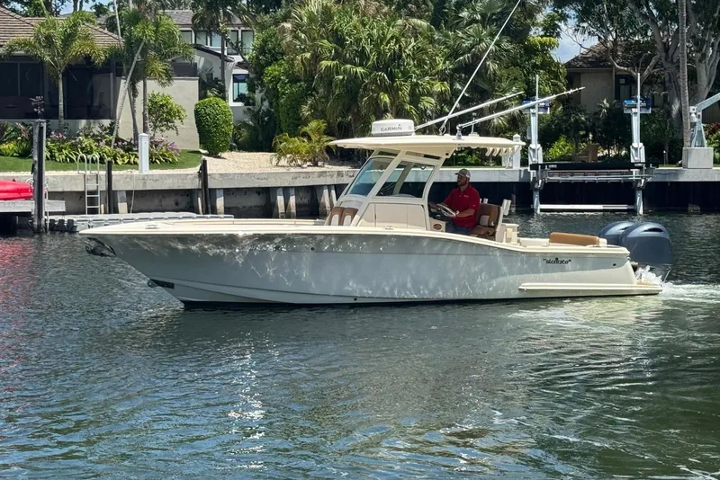 Slide: The Image of 2013 Scout 275 LXF boat cruising on a sunny waterfront near docks and greenery. - 15