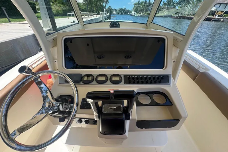Slide: The Image of 2013 Scout 275 LXF boat helm with steering wheel and control panel by the water. - 17