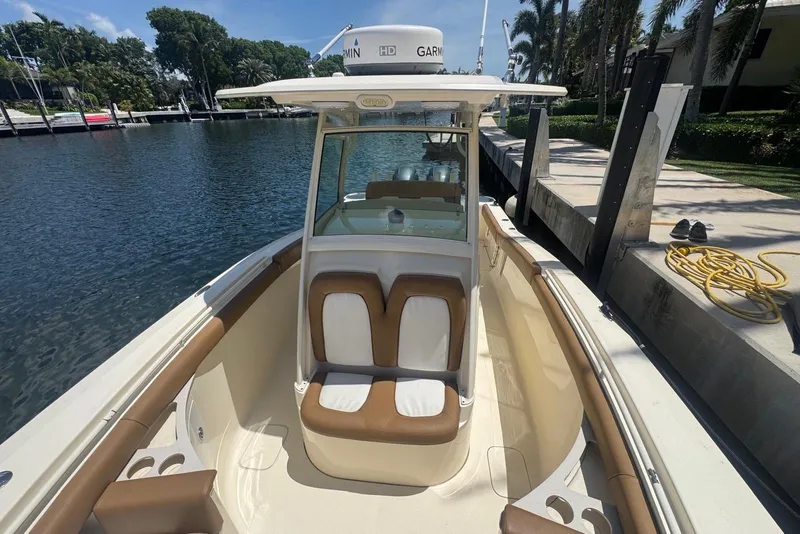 Slide: The Image of 2013 Scout 275 LXF boat docked, featuring cushioned seating and Garmin equipment. - 19