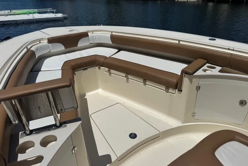 Slide: The Image of 2013 Scout 275 LXF boat interior with brown and white seating, cup holders, and storage. - 25