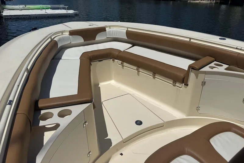 Slide: The Image of 2013 Scout 275 LXF boat interior with brown and white seating, docked by the water. - 26