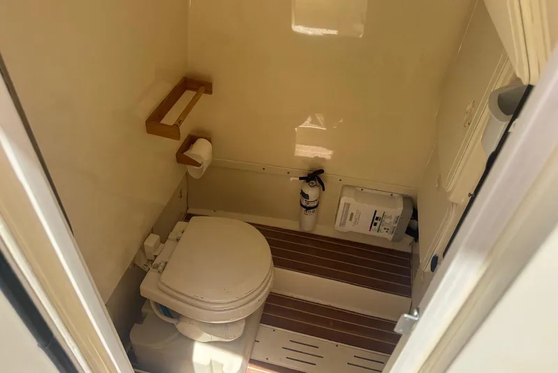 Slide: The Image of 2013 Scout 275 LXF boat bathroom with toilet, wooden flooring, and fire extinguisher. - 27