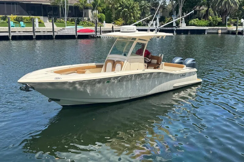 Slide: The Image of 2013 Scout 275 LXF boat on calm water near a dock, surrounded by greenery. - 9