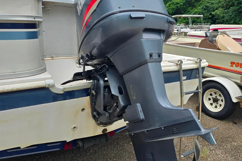 Slide: The Image of Outboard motor on a 1999 Hurricane 226R boat, parked with trailers nearby. - 6