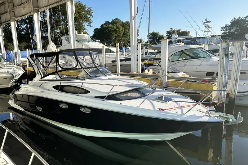 Slide: The Image of 2008 Regal 3360 Window Express boat docked in marina, featuring sleek black and white design. - 2