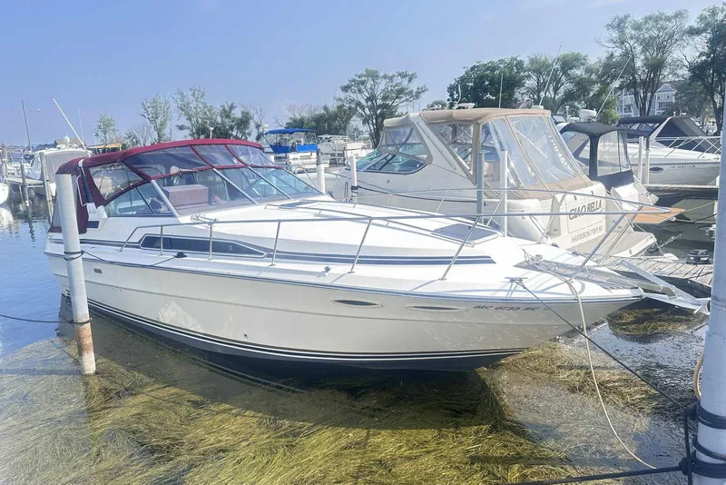 The Image of 1987 Sea Ray 340 Sundancer docked at marina, featuring sleek design and red canopy. - 0