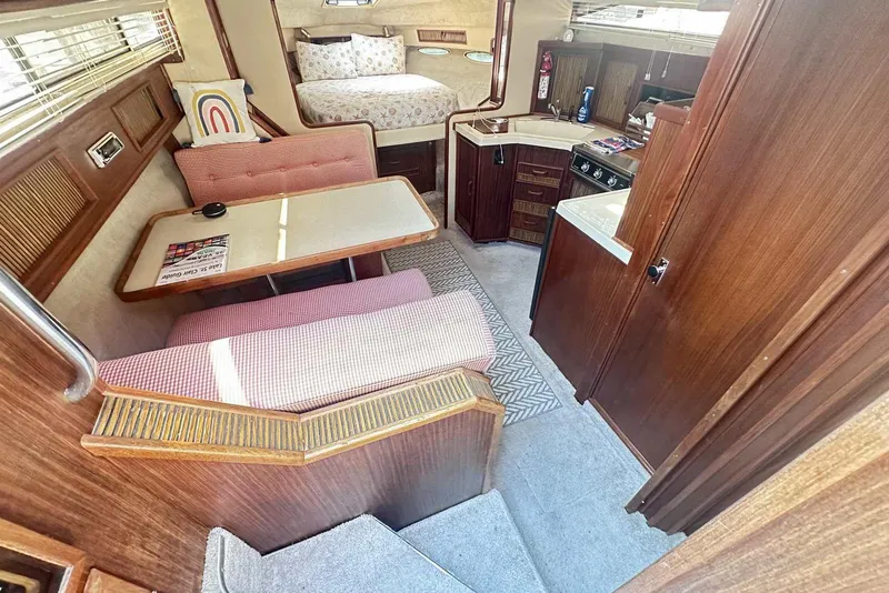 Slide: The Image of Interior of 1987 Sea Ray 340 Sundancer with cozy seating, table, and compact kitchen. - 15
