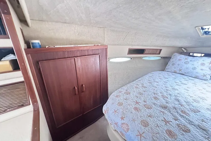 Slide: The Image of 1987 Sea Ray 340 Sundancer cabin interior with bed and wooden cabinet. - 22