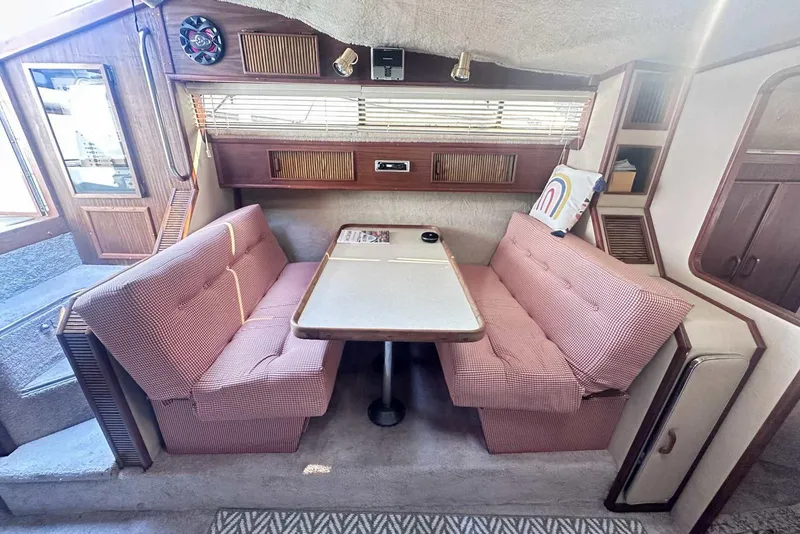 Slide: The Image of Interior of 1987 Sea Ray 340 Sundancer with cozy dining area and pink seating. - 23
