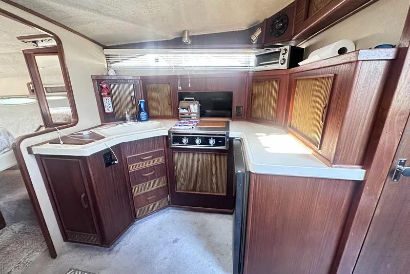 Slide: The Image of 1987 Sea Ray 340 Sundancer interior kitchen with wooden cabinets and modern appliances. - 25