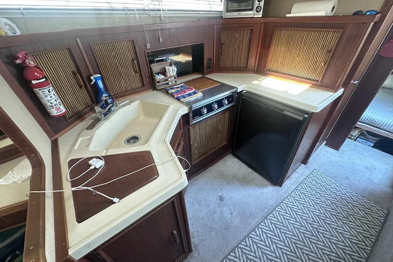 Slide: The Image of 1987 Sea Ray 340 Sundancer kitchen with sink, stove, and refrigerator. - 26