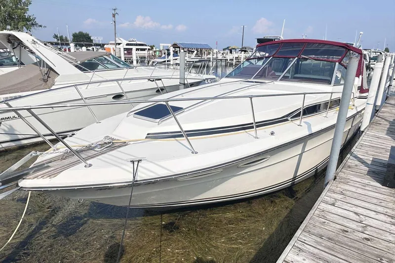 Slide: The Image of 1987 Sea Ray 340 Sundancer docked at a marina, featuring sleek design and spacious deck. - 3