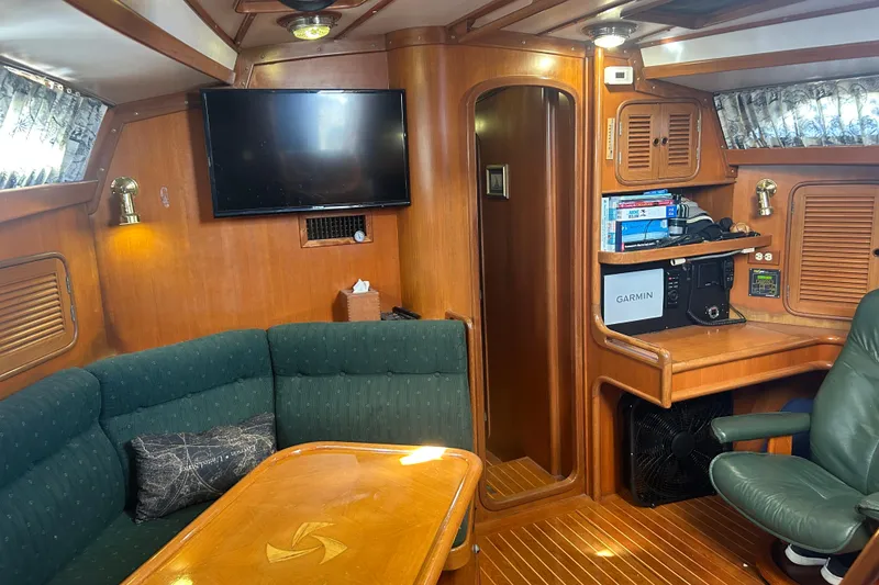 Slide: The Image of Interior of 1995 Tayana 48 yacht with wood paneling, green seating, and navigation equipment. - 10