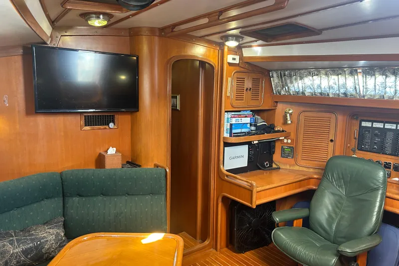Slide: The Image of Interior of 1995 Tayana 48 yacht with wood paneling, green seating, and navigation equipment. - 11