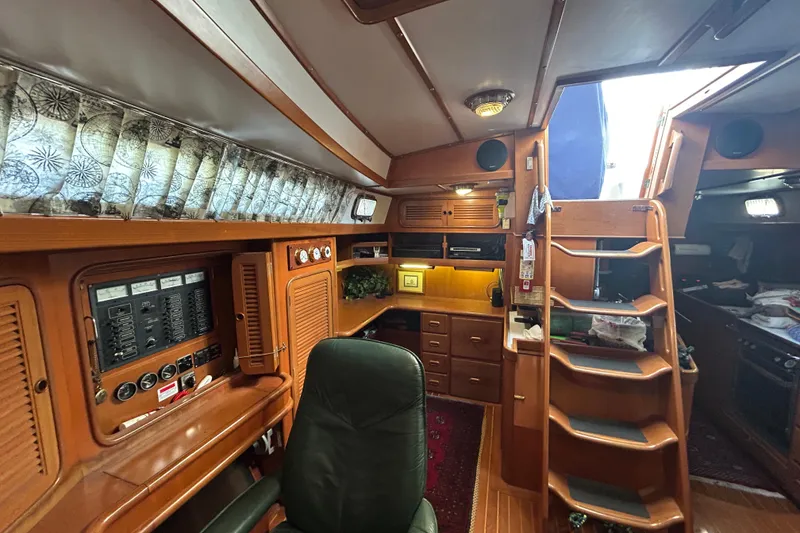 Slide: The Image of Interior of a 1995 Tayana 48 yacht featuring wooden cabinetry and a navigation station. - 20
