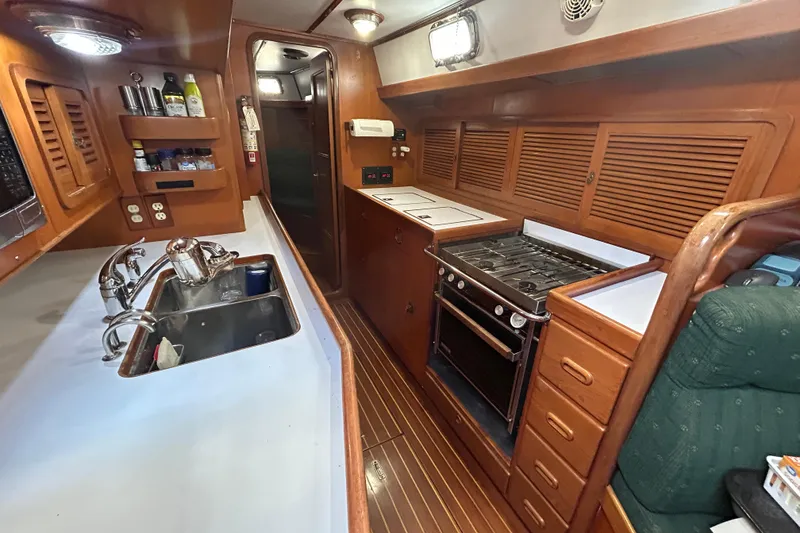 Slide: The Image of Interior of 1995 Tayana 48 yacht kitchen with stove, sink, and wooden cabinetry. - 23